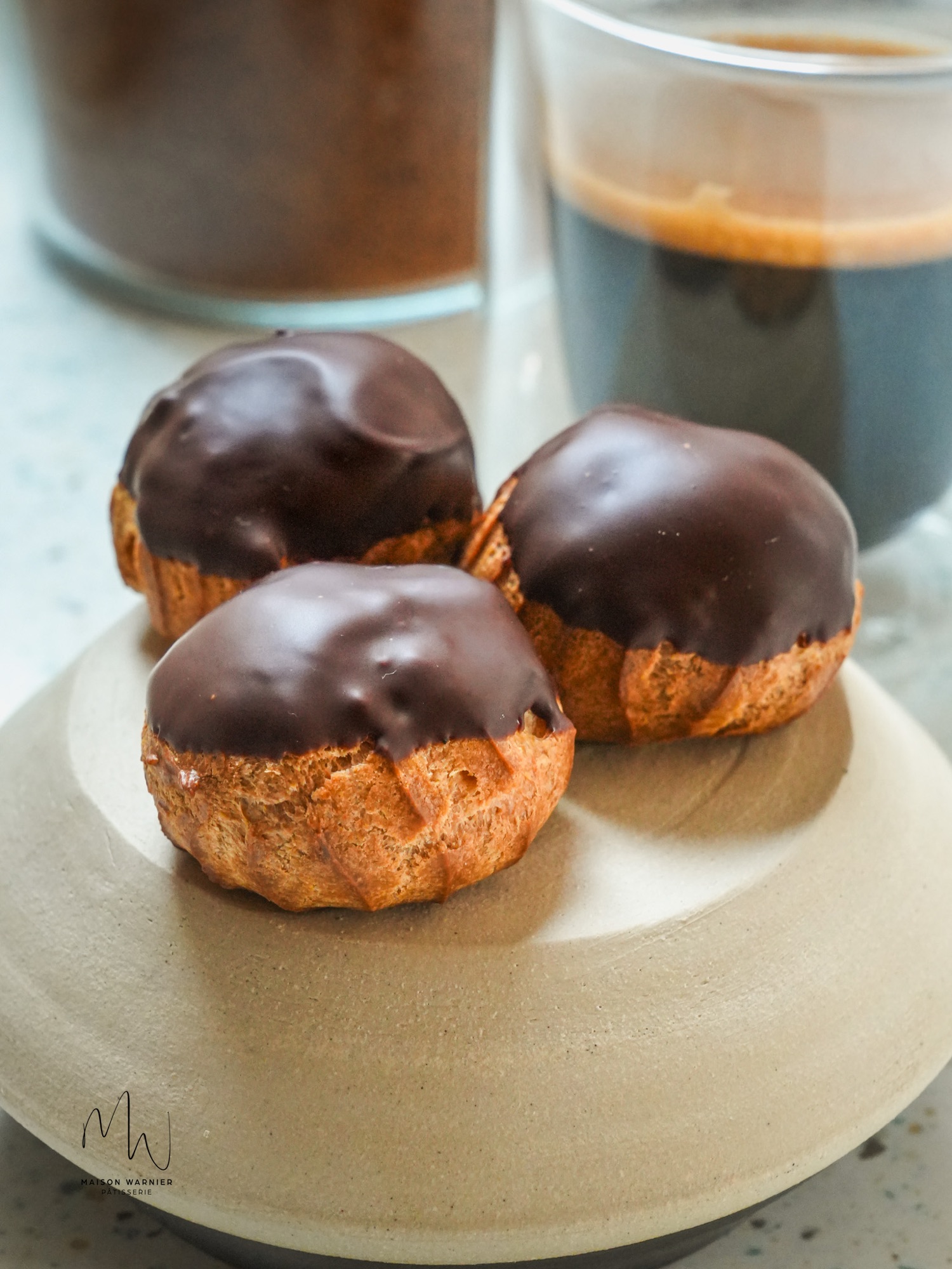Choux nappés de chocolat noir, servis avec un café à l'atelier Maison Warnier